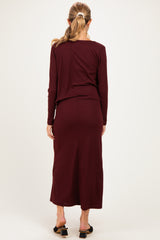 woman wearing a burgundy long sleeve maternity dress with a fitted silhouette, showing the back view
