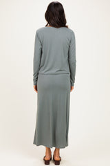 woman wearing a long sleeve light green maxi dress, viewed from the back, with a fitted waist and a flowy skirt