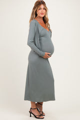 woman wearing a slate gray maternity cardigan dress and holding her baby bump