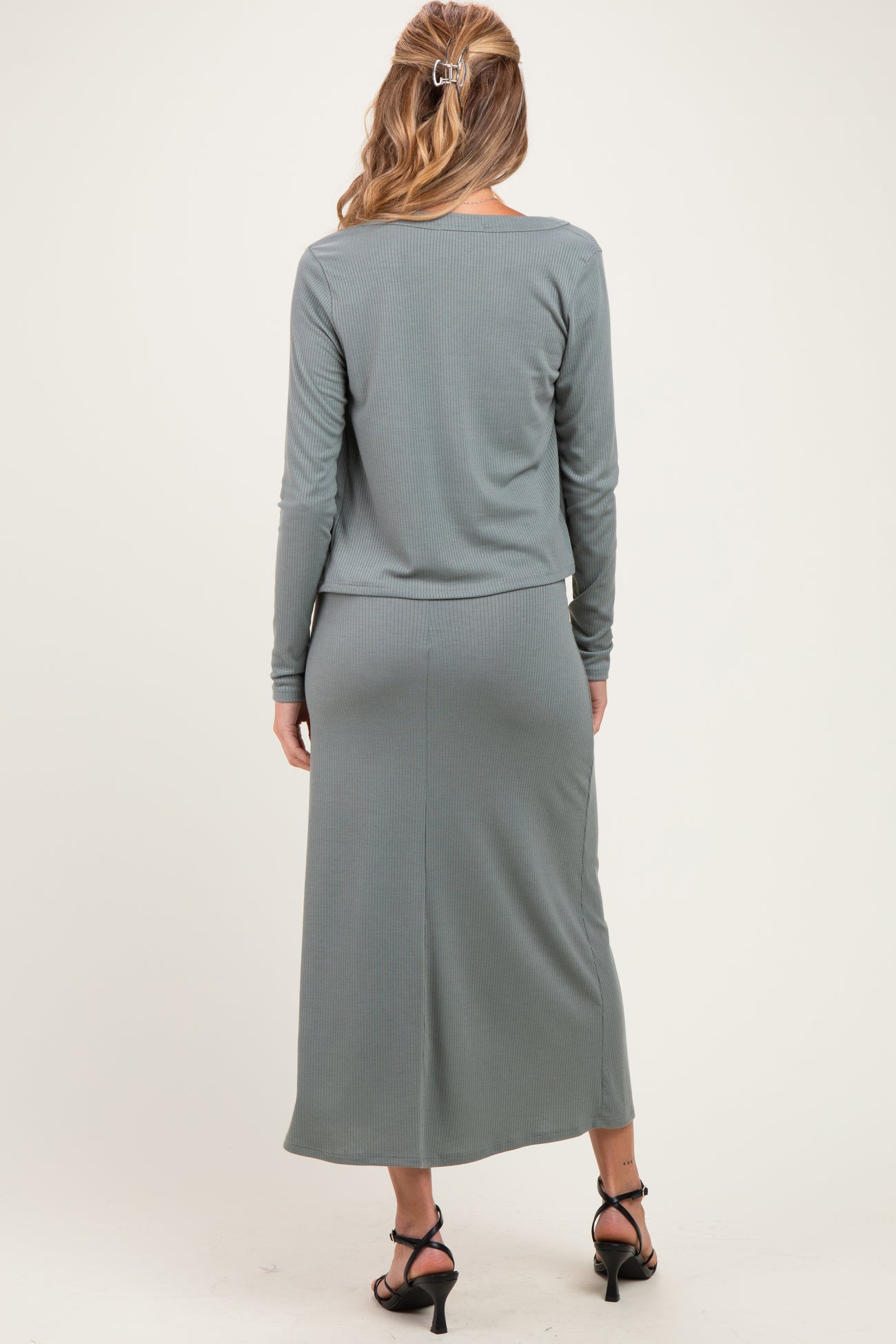 woman wearing a long sleeve gray ribbed maternity dress with a fitted skirt and styled hair