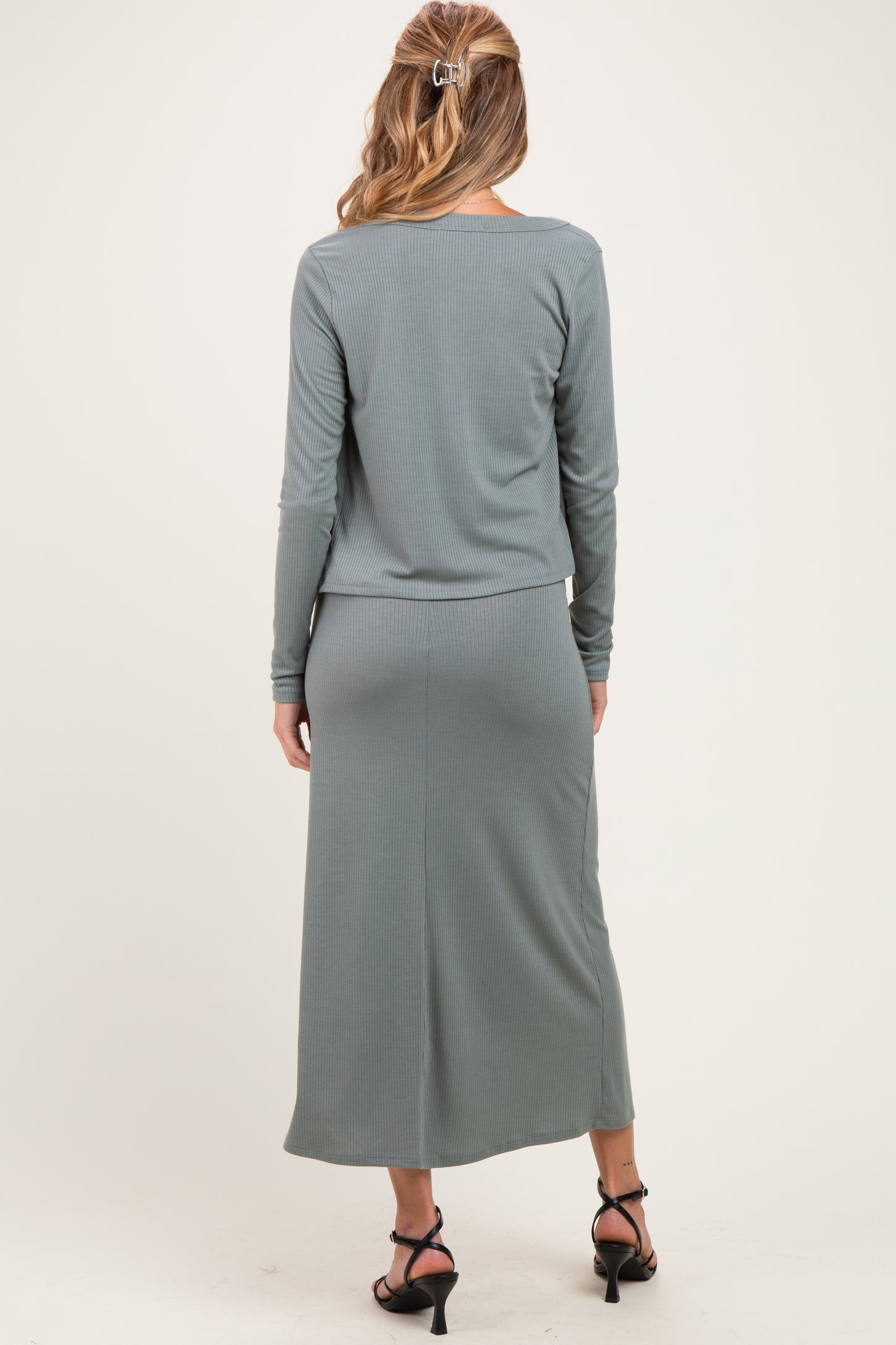 woman wearing a long sleeve gray ribbed maternity dress with a fitted skirt and styled hair