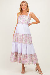 woman wearing a lavender and floral patterned maxi maternity dress with tiered layers and spaghetti straps, showing off her baby bump
