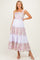 woman wearing a lavender and floral patterned maxi maternity dress with tiered layers and spaghetti straps, showing off her baby bump