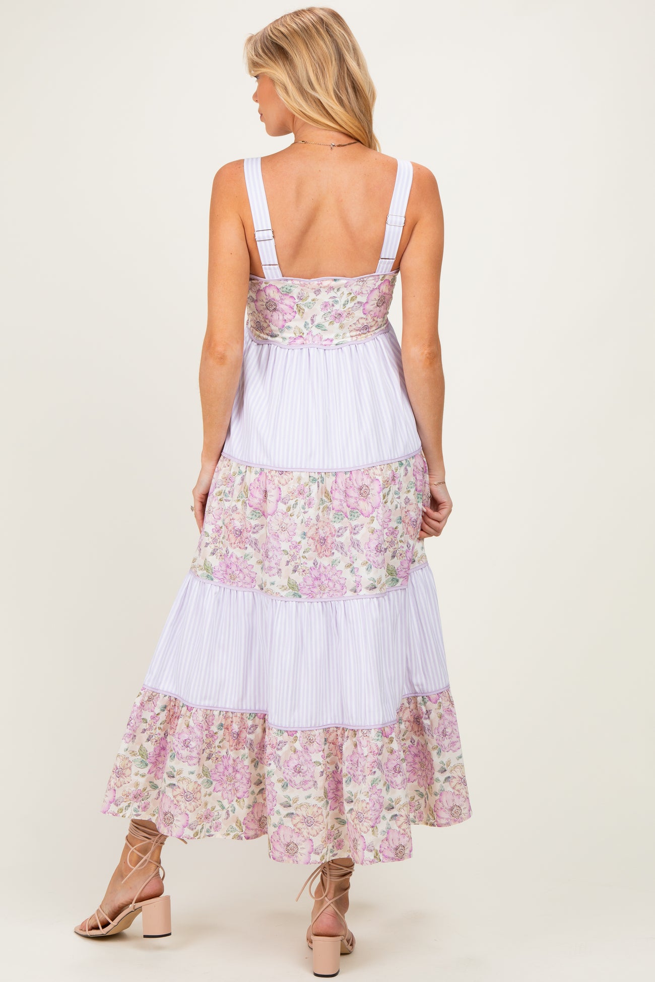 woman wearing a light purple floral print maternity maxi dress with tiered ruffles and a low back