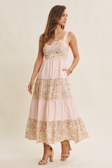 woman wearing a floral tiered maxi dress with pink stripes and a fitted bodice, standing elegantly