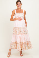 woman wearing a pink floral and striped maternity maxi dress and holding her baby bump