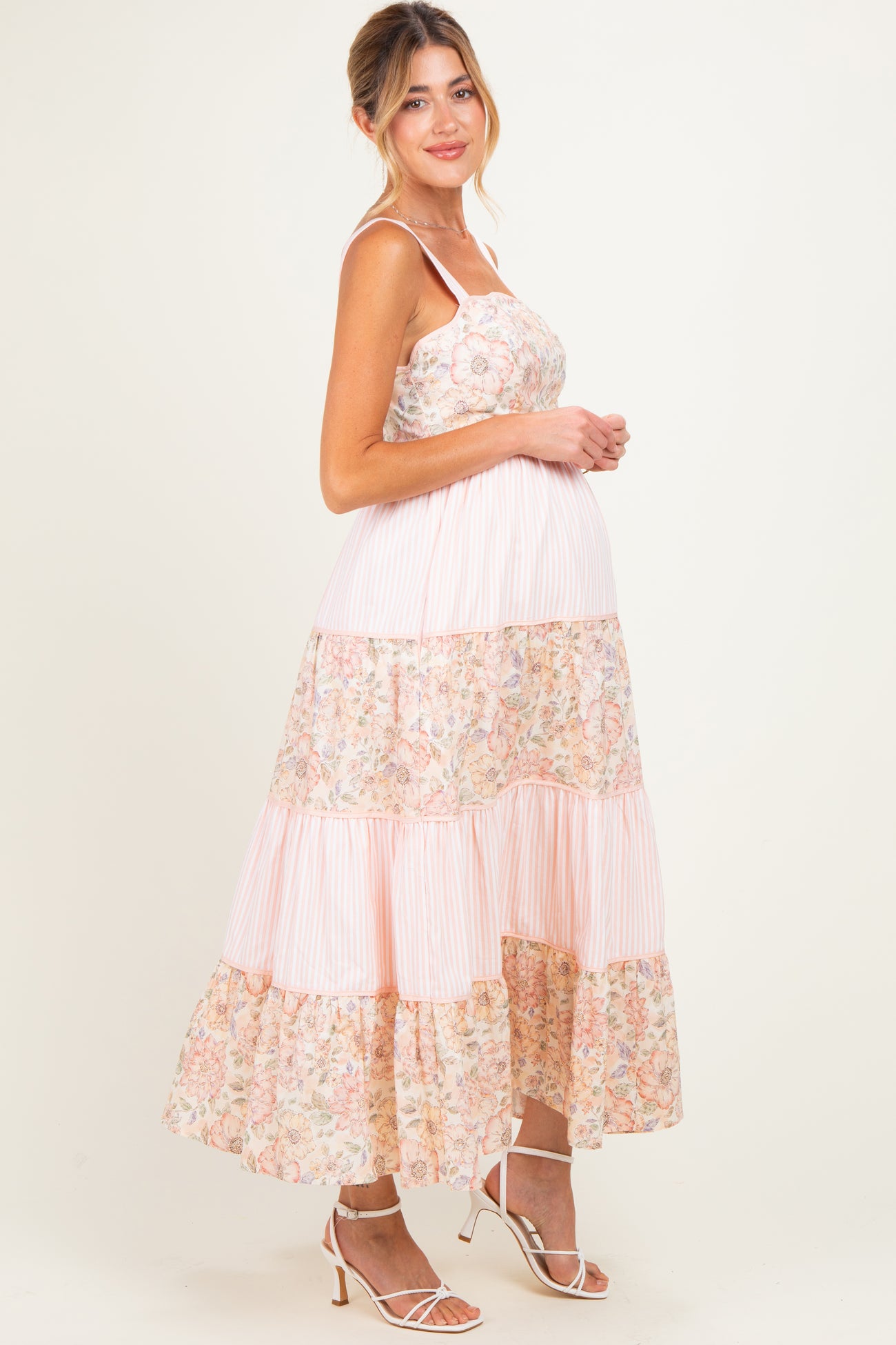 woman wearing a pink floral maternity maxi dress with tiered ruffles and a baby bump visible