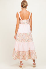 woman wearing a back view of a floral patterned maternity maxi dress with tiered ruffles and adjustable straps