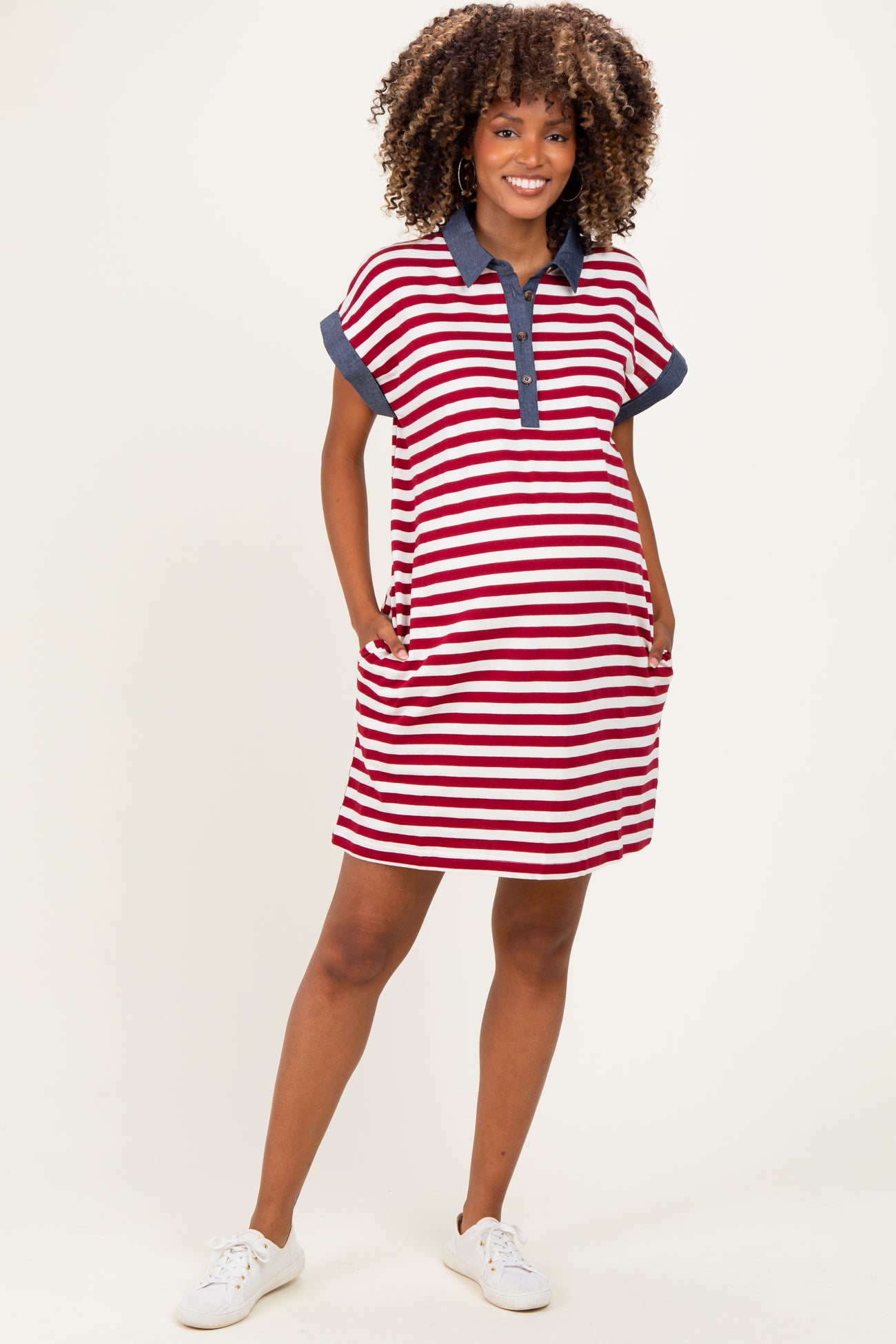 woman wearing a red and white striped maternity polo dress with navy collar and pockets, showcasing her baby bump