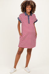 woman wearing a red and white striped maternity polo dress with navy collar and pockets, showcasing her baby bump