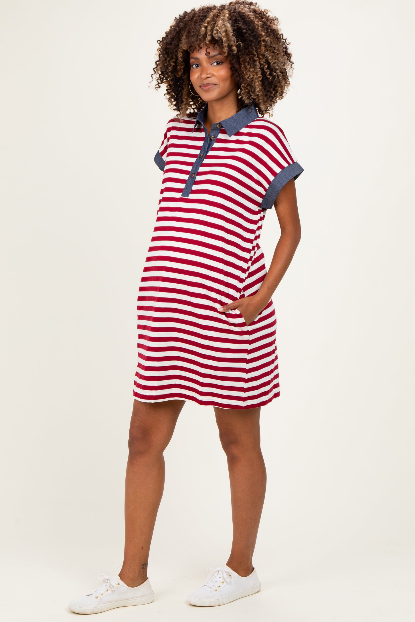 woman wearing a red and white striped maternity dress with a navy collar and pockets, showcasing her baby bump