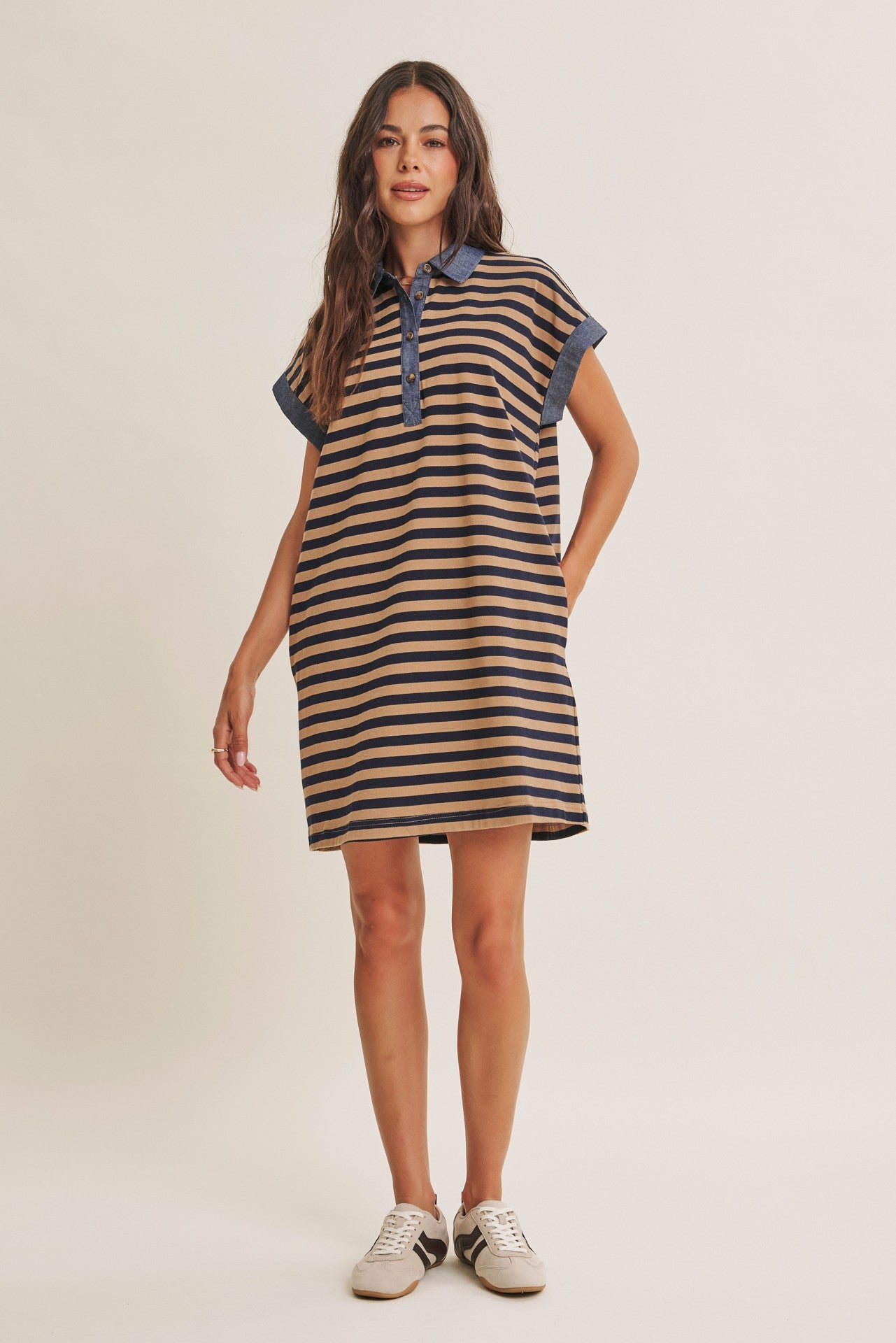 woman wearing a striped brown and navy polo dress with short sleeves and a collar, styled casually with sneakers