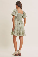 woman wearing a back view of a pastel green floral sundress with puff sleeves and a ruffled hem