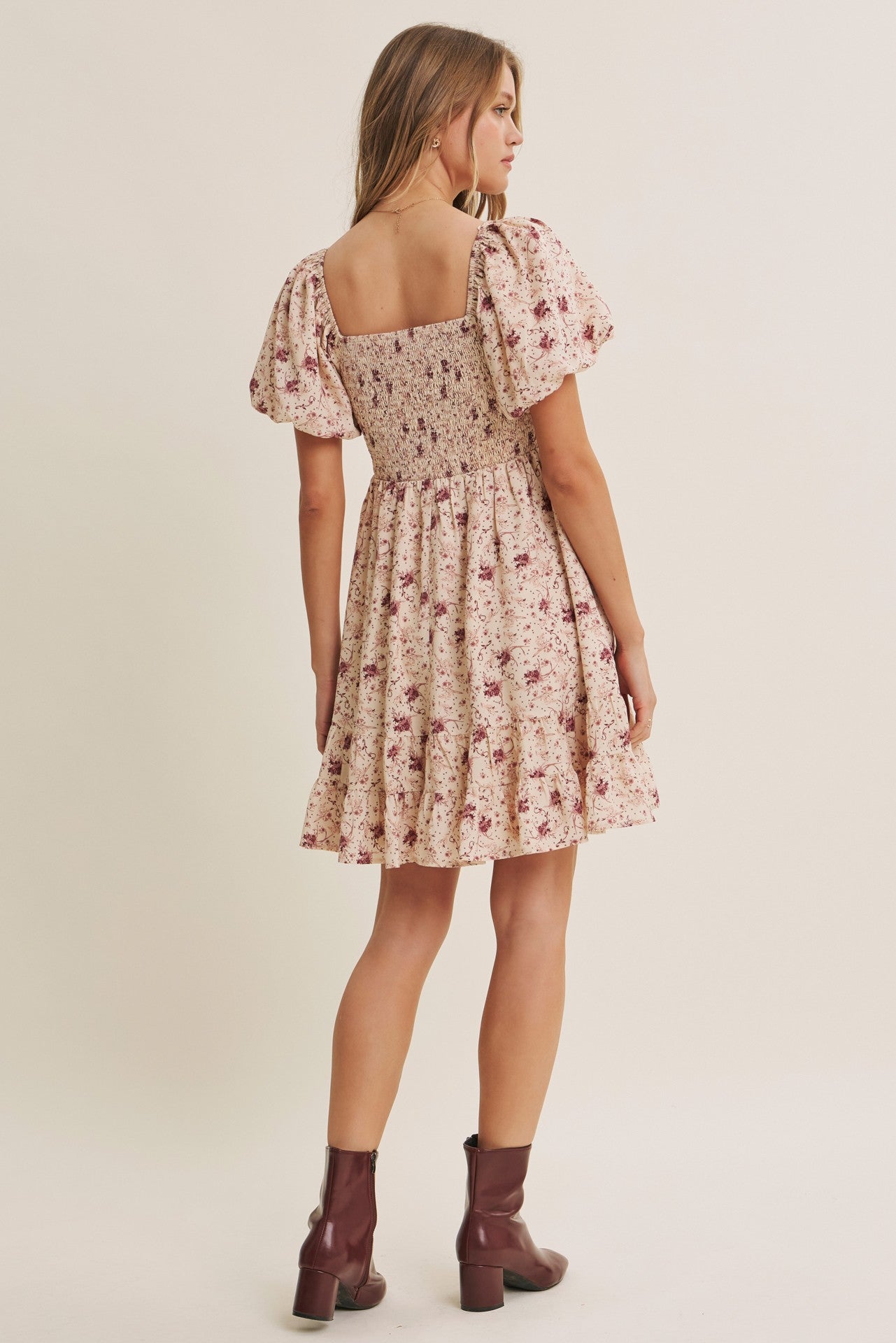 woman wearing a floral smocked sundress with puff sleeves and a tiered skirt, shown from the back