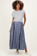 woman wearing a gray cropped maternity top and a long blue plaid maternity skirt with pockets