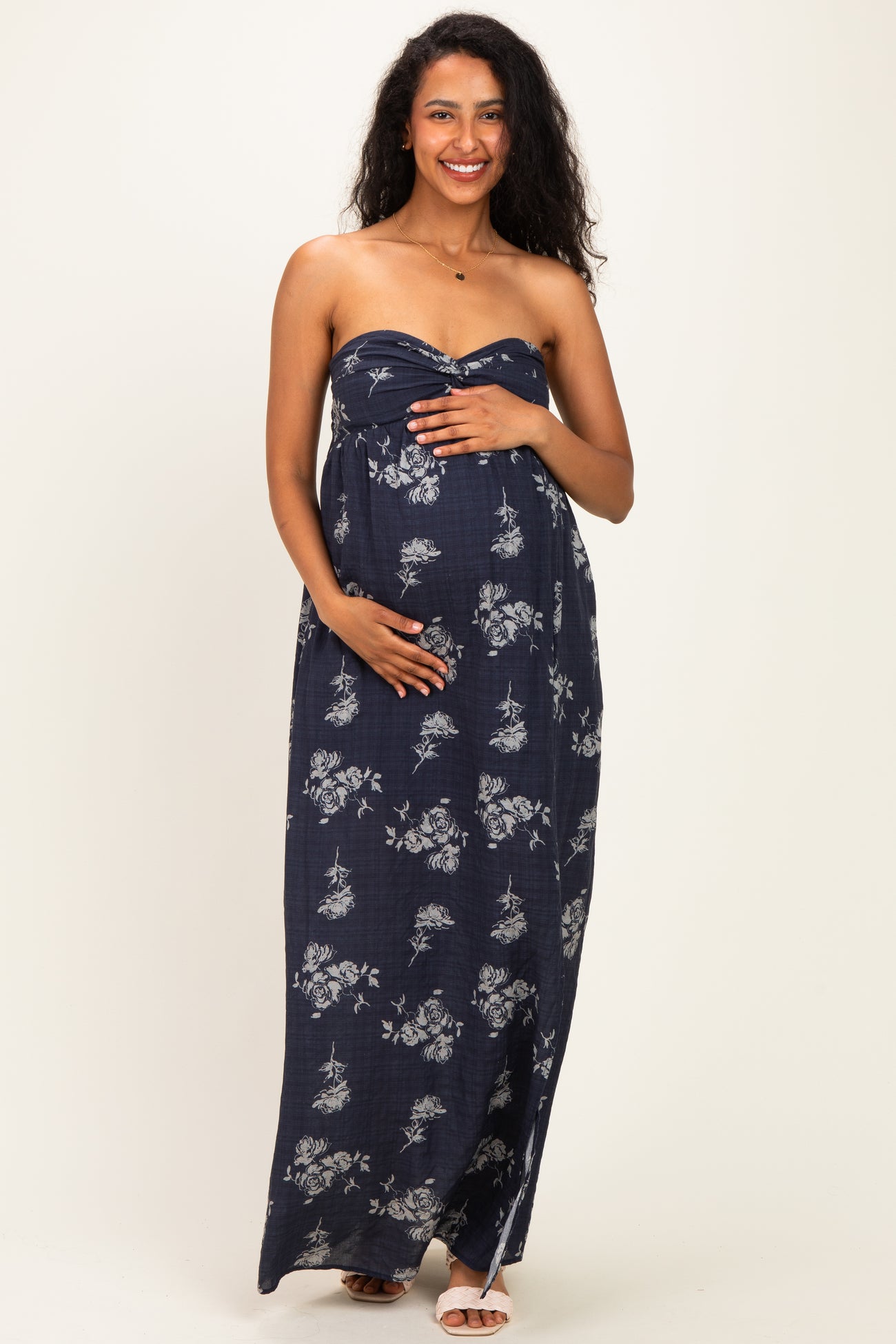 woman wearing a strapless navy floral maxi dress and holding her baby bump