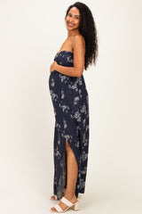 woman wearing a navy floral strapless maternity maxi dress and holding her baby bump