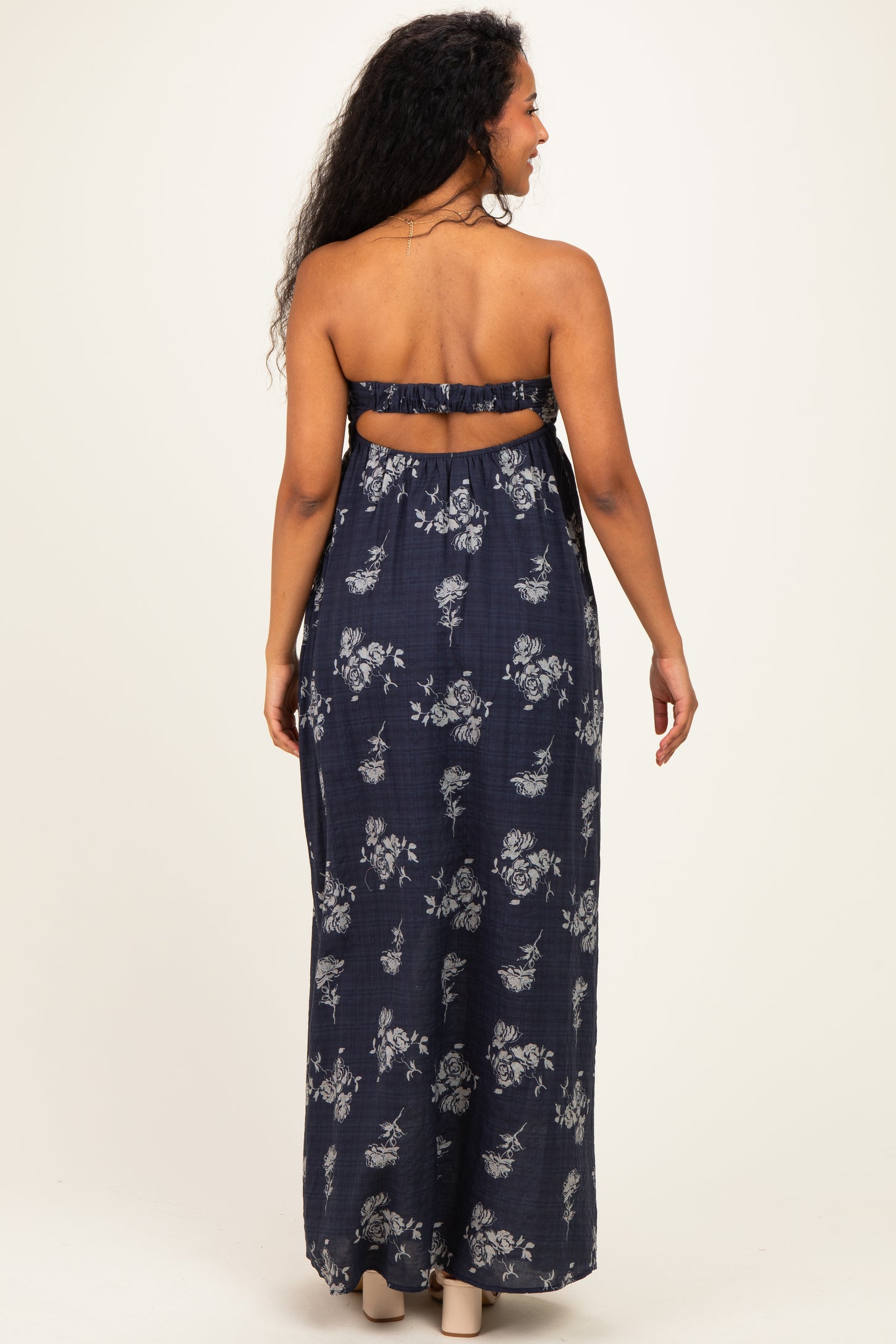 woman wearing a navy floral strapless maternity maxi dress, showing a loose fit and back detail