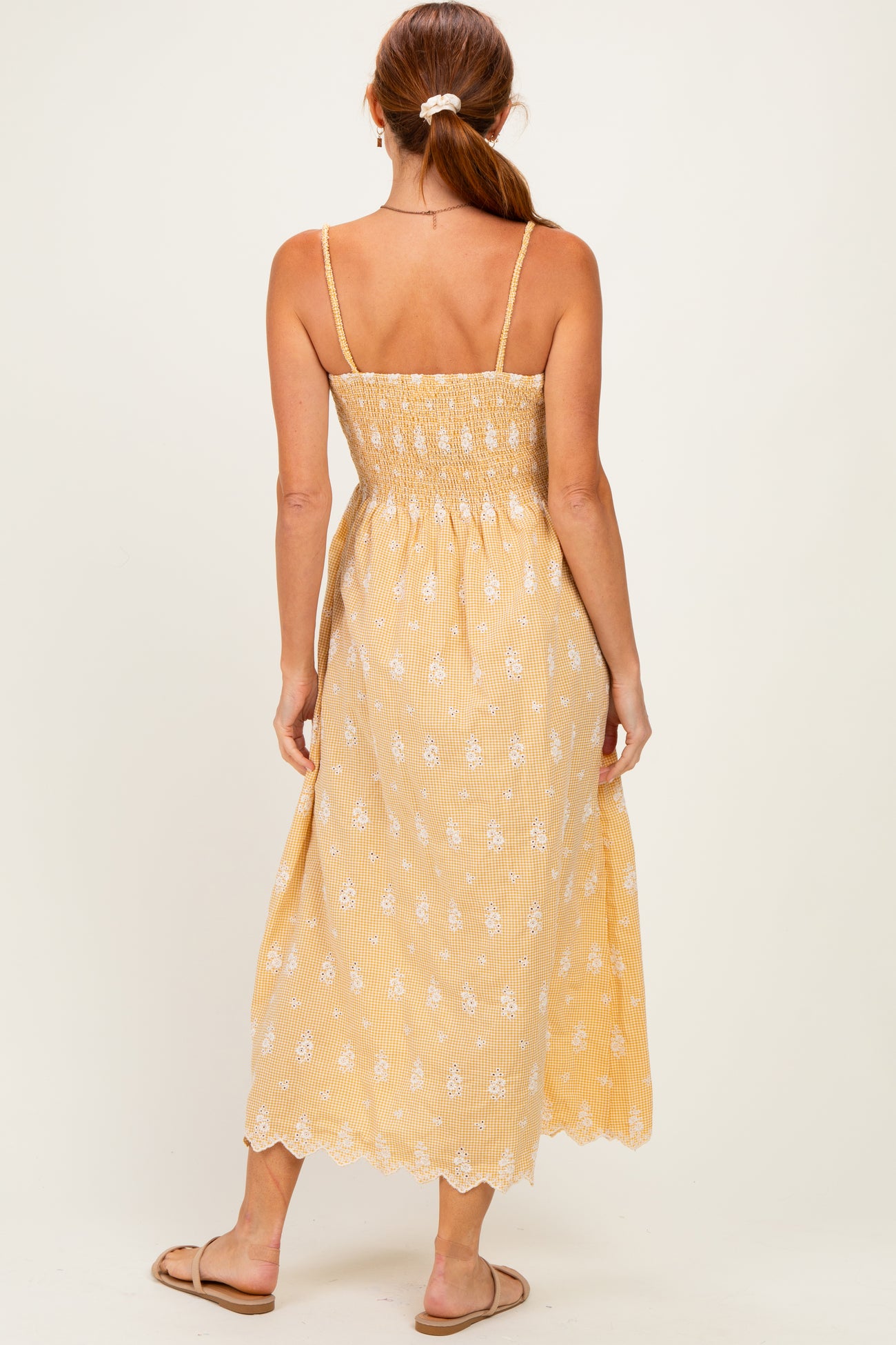 woman wearing a yellow floral smocked back maxi dress with adjustable straps and a flowy silhouette