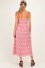 woman wearing a pink and white floral maternity midi dress with spaghetti straps and a smocked bodice, showing her baby bump
