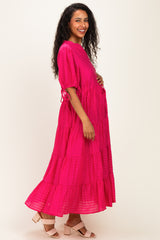 woman wearing a bright pink tiered maternity dress, smiling and showing a baby bump