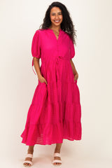 woman wearing a bright pink tiered maternity dress with short puff sleeves and pockets
