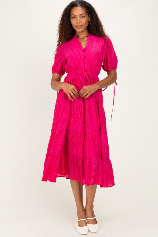 woman wearing a bright pink tiered midi dress with short sleeves and a tie waist detail