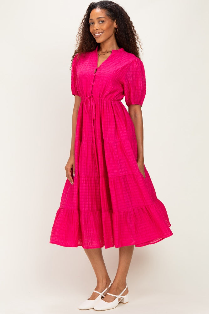 woman wearing a vibrant pink button-up midi dress with short puff sleeves and a tiered skirt