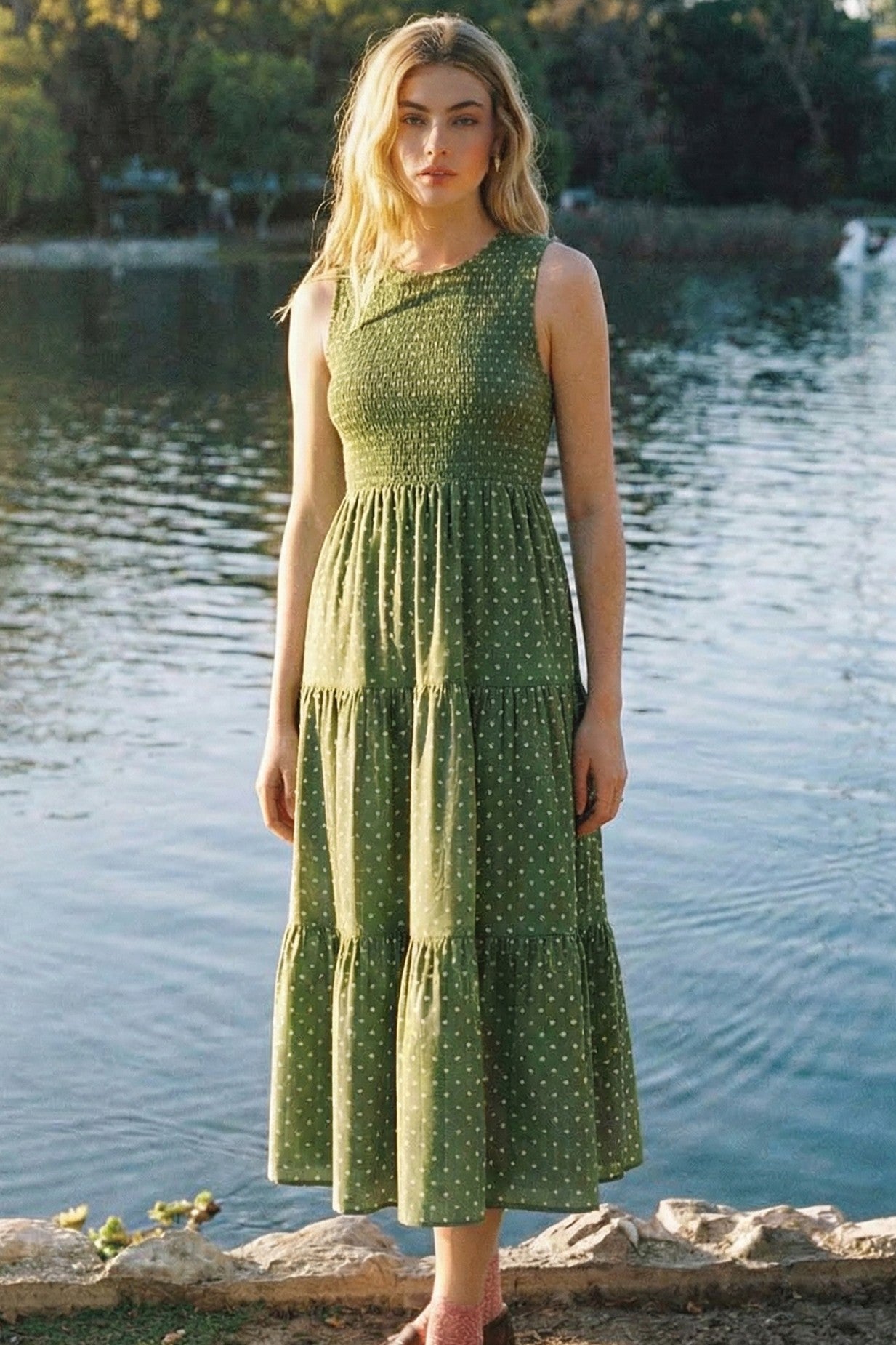 woman wearing a green polka dot tiered midi dress posed by a lake