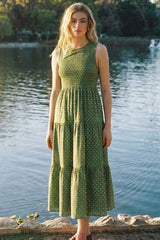 woman wearing a green polka dot tiered midi dress posed by a lake