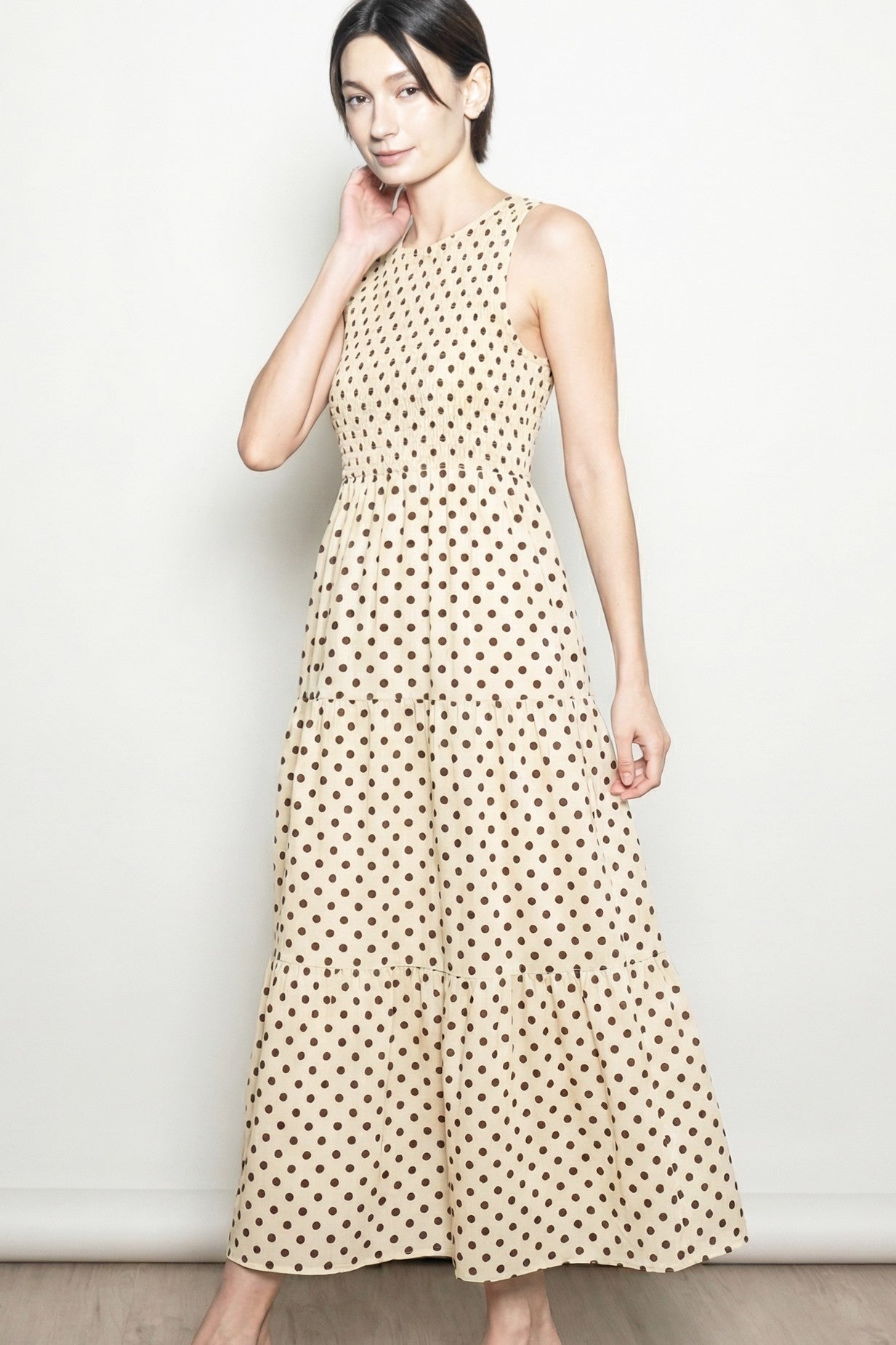woman wearing a beige polka dot maxi dress with a fitted bodice and tiered skirt