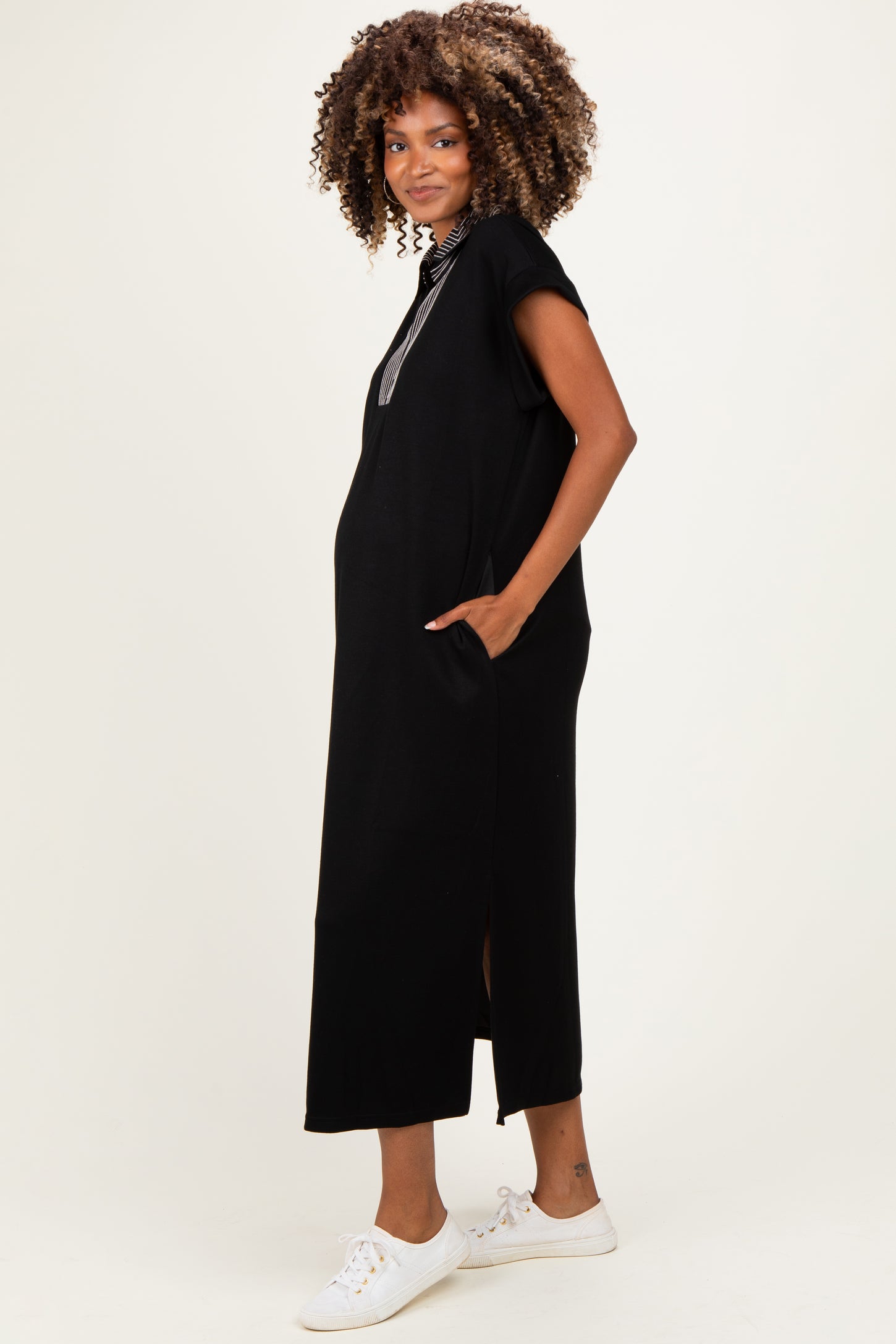 woman wearing a black maternity maxi dress with short sleeves and side pockets, showing a baby bump