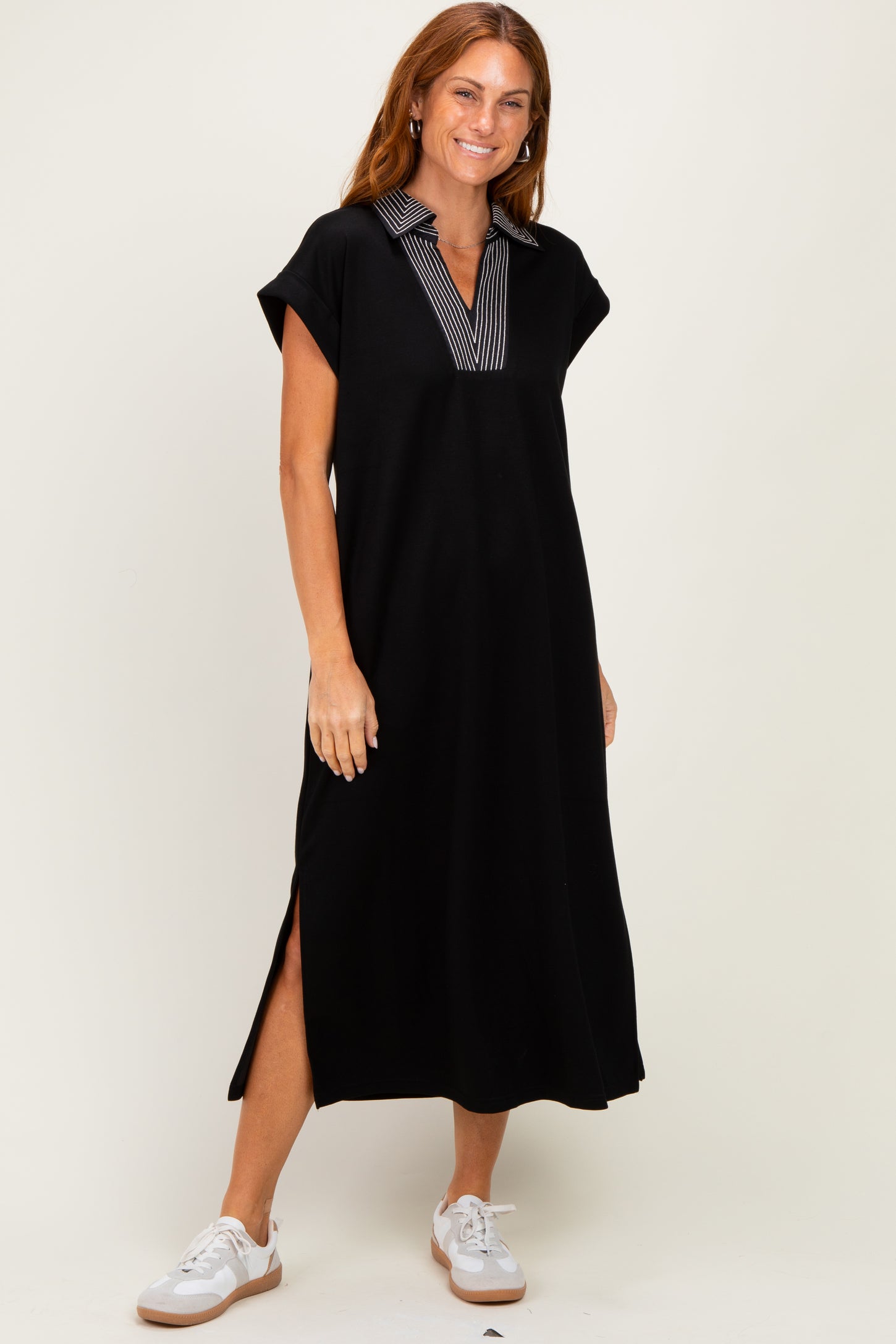 woman wearing a black cap sleeve midi dress with a striped collar and side slits
