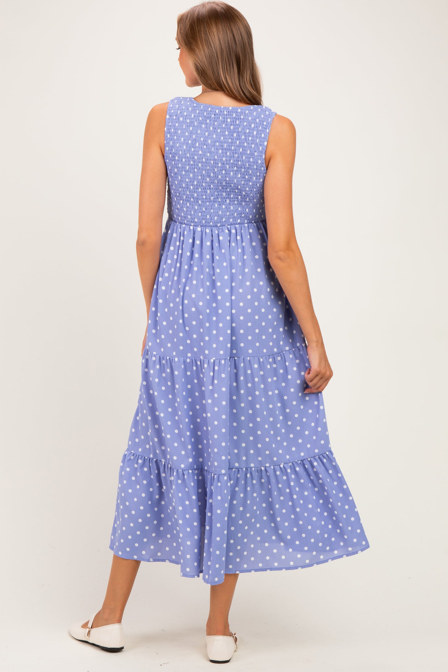 woman wearing a blue polka dot maternity dress with a smocked bodice and tiered skirt, shown from the back