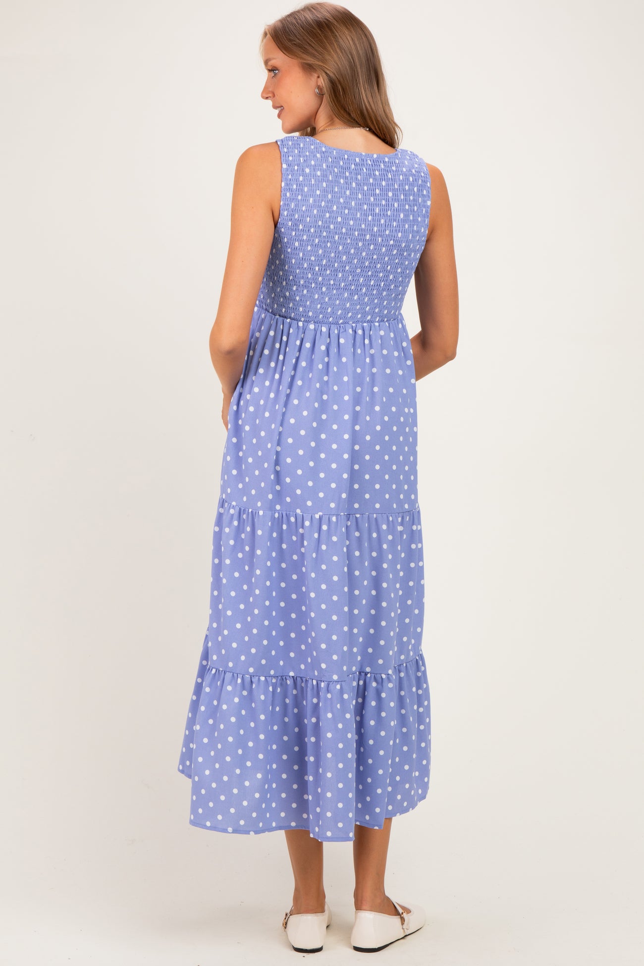 woman wearing a blue maternity maxi dress with white polka dots and a smocked back detail
