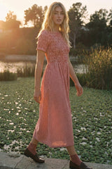 woman wearing a red and white gingham midi dress with short sleeves, standing by a pond during sunset