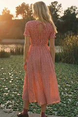 woman wearing a red and white gingham midi dress with a smocked back, standing by a pond at sunset