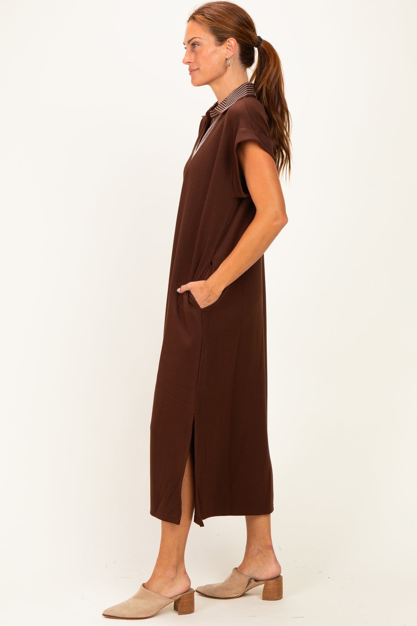 woman wearing a brown maxi dress with short sleeves and side pockets, standing sideways with a relaxed fit