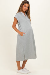 woman wearing a gray maternity polo dress with pockets and side slits, showing her baby bump