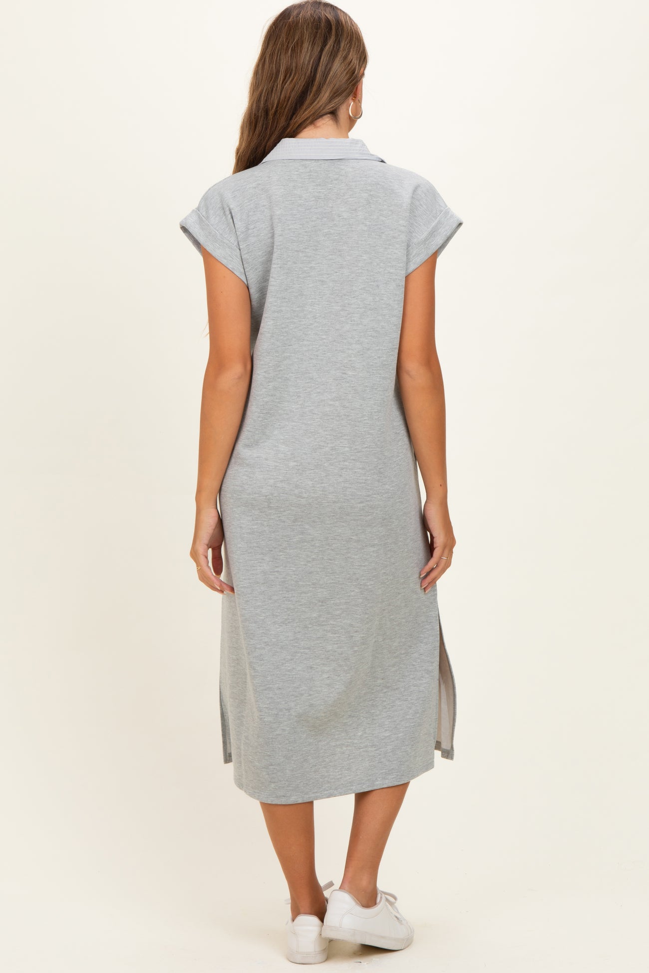 woman wearing a gray short sleeve maternity dress with side slits and a relaxed fit, viewed from the back