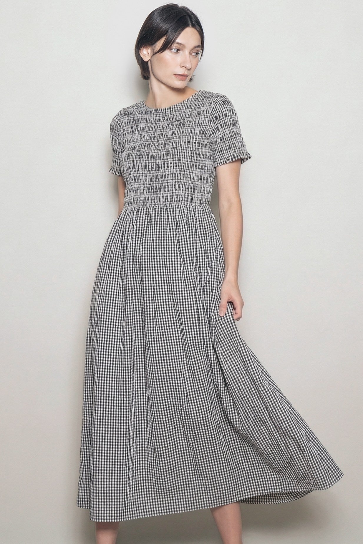 woman wearing a black and white gingham patterned midi dress with smocked bodice and short sleeves