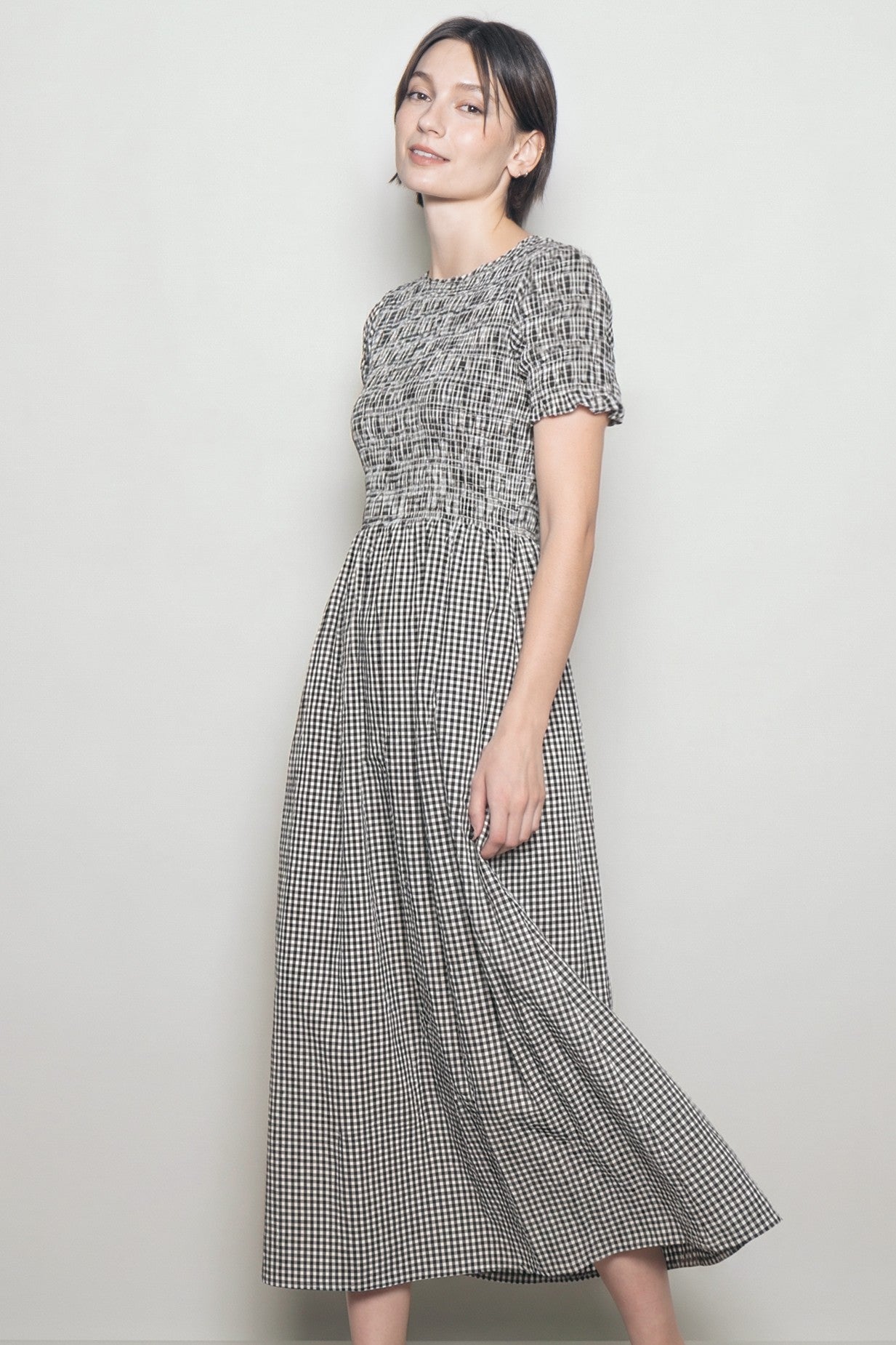 woman wearing a black and white gingham maxi dress with short sleeves and a smocked bodice