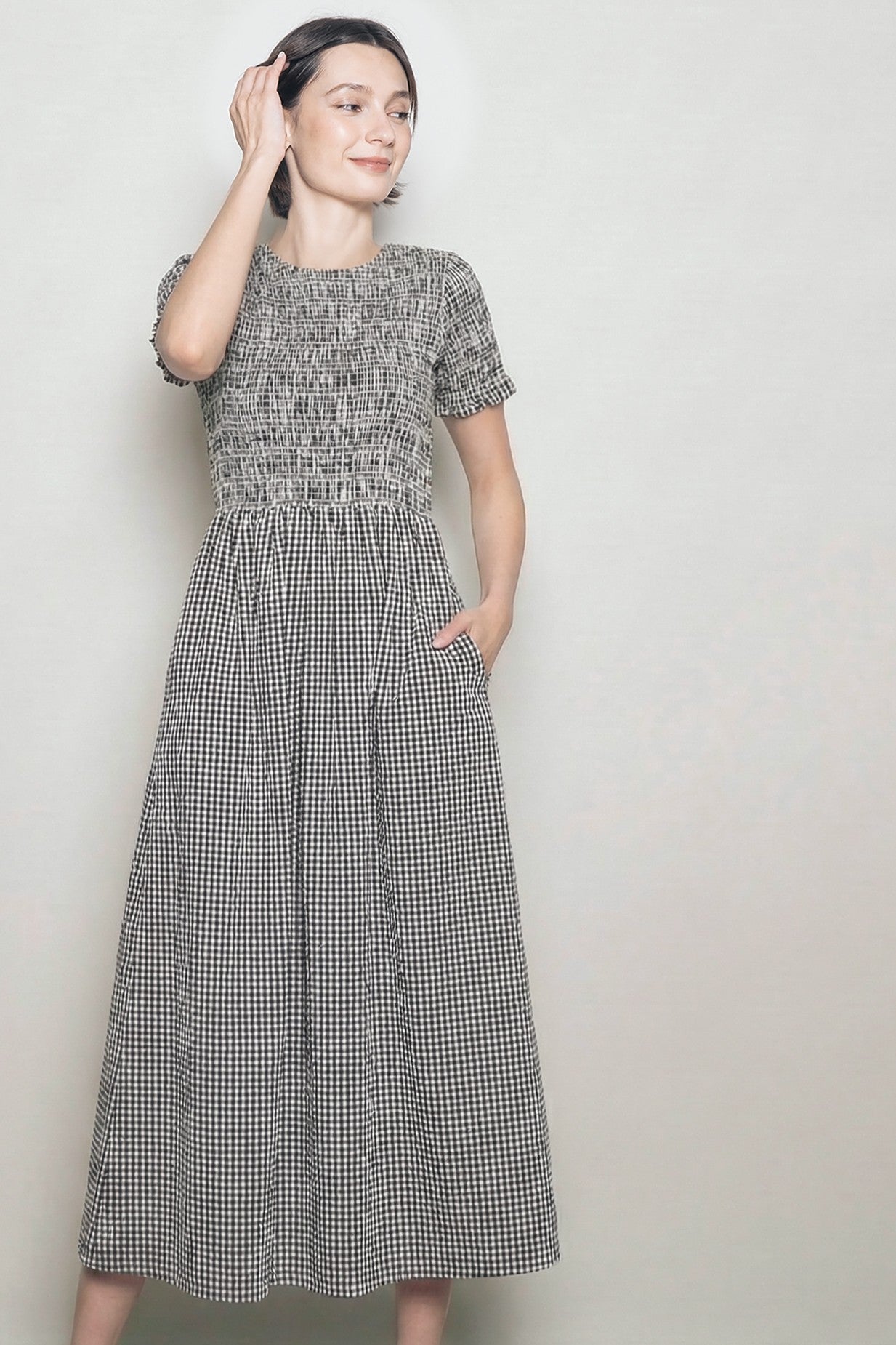 woman wearing a black and white gingham smocked maxi dress with short sleeves and pockets