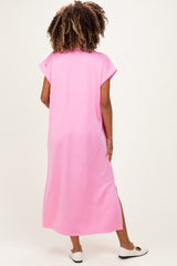 woman wearing a long pink maternity dress with short sleeves and side slits, viewed from the back