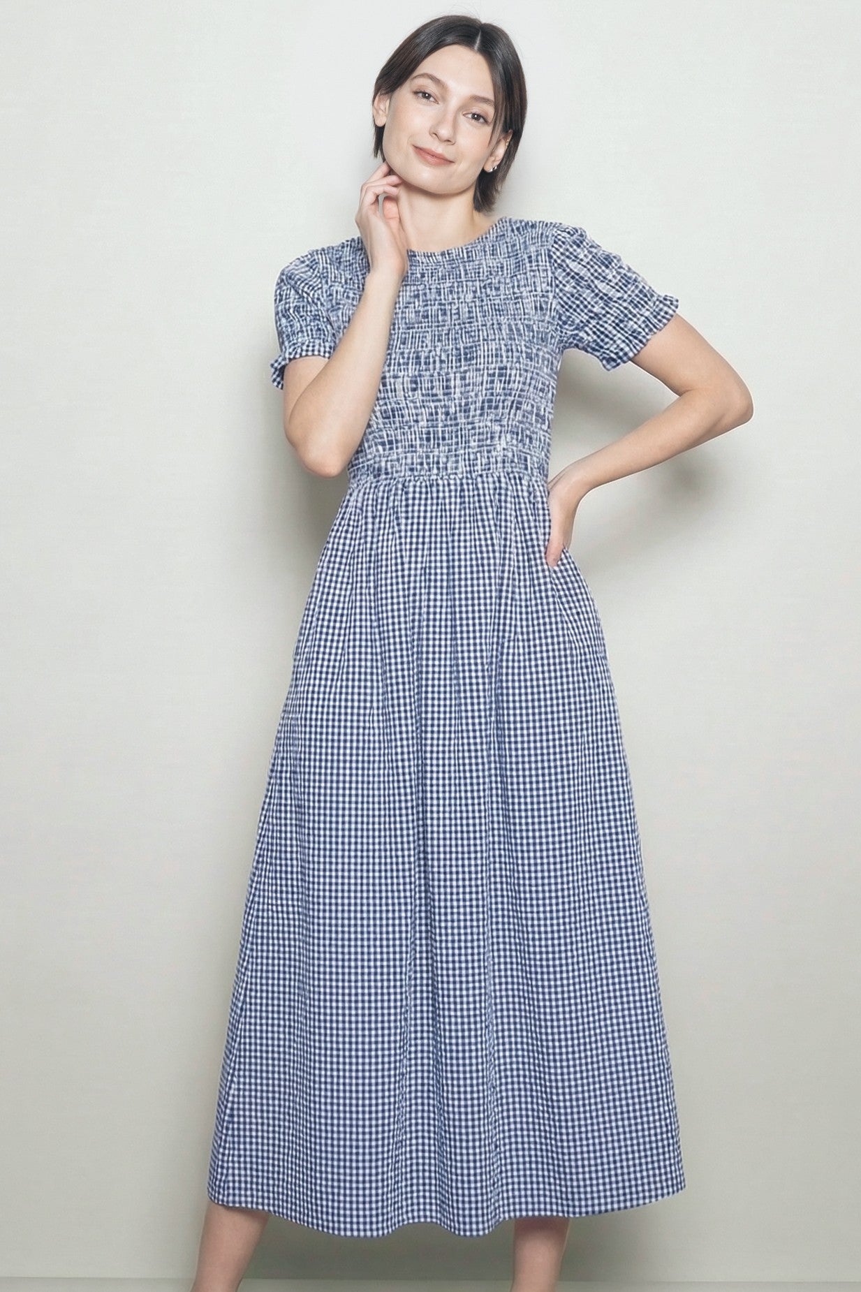 woman wearing a navy blue gingham maxi dress with short sleeves and a smocked bodice