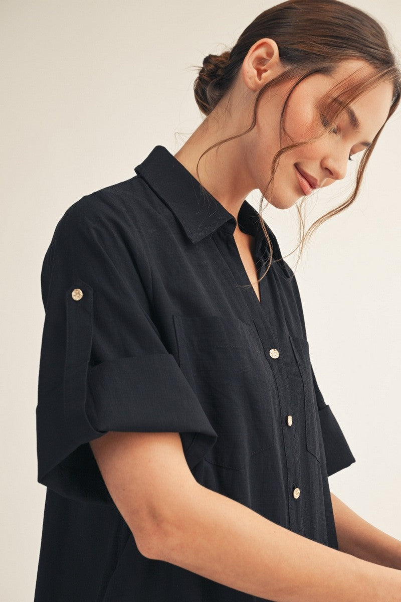 woman wearing a black short sleeve button-up shirt with a collar and two front pockets