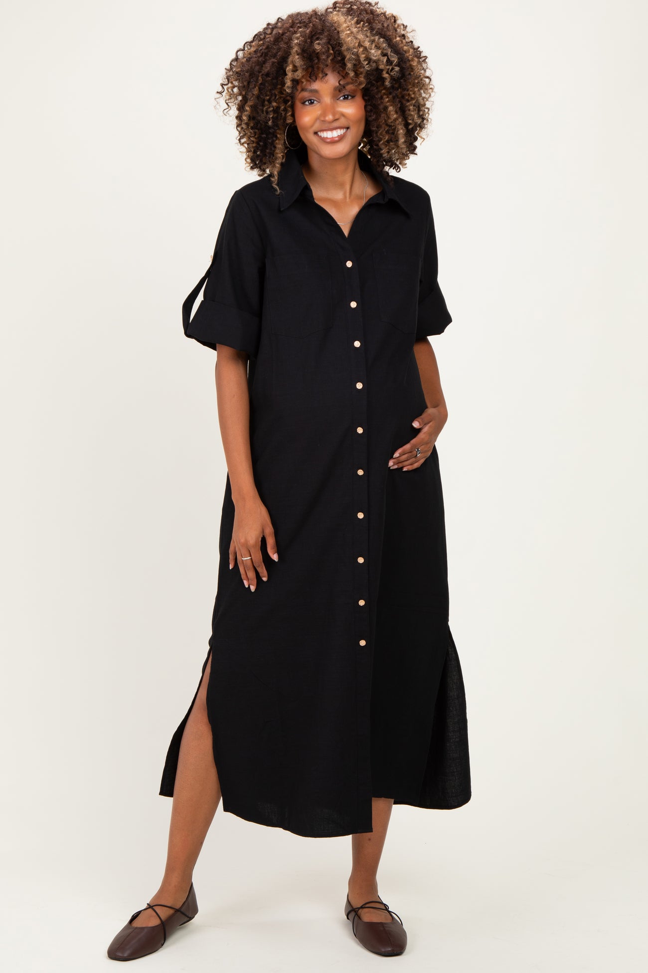 woman wearing a black button-up maternity dress with short sleeves and side slits, highlighting her baby bump