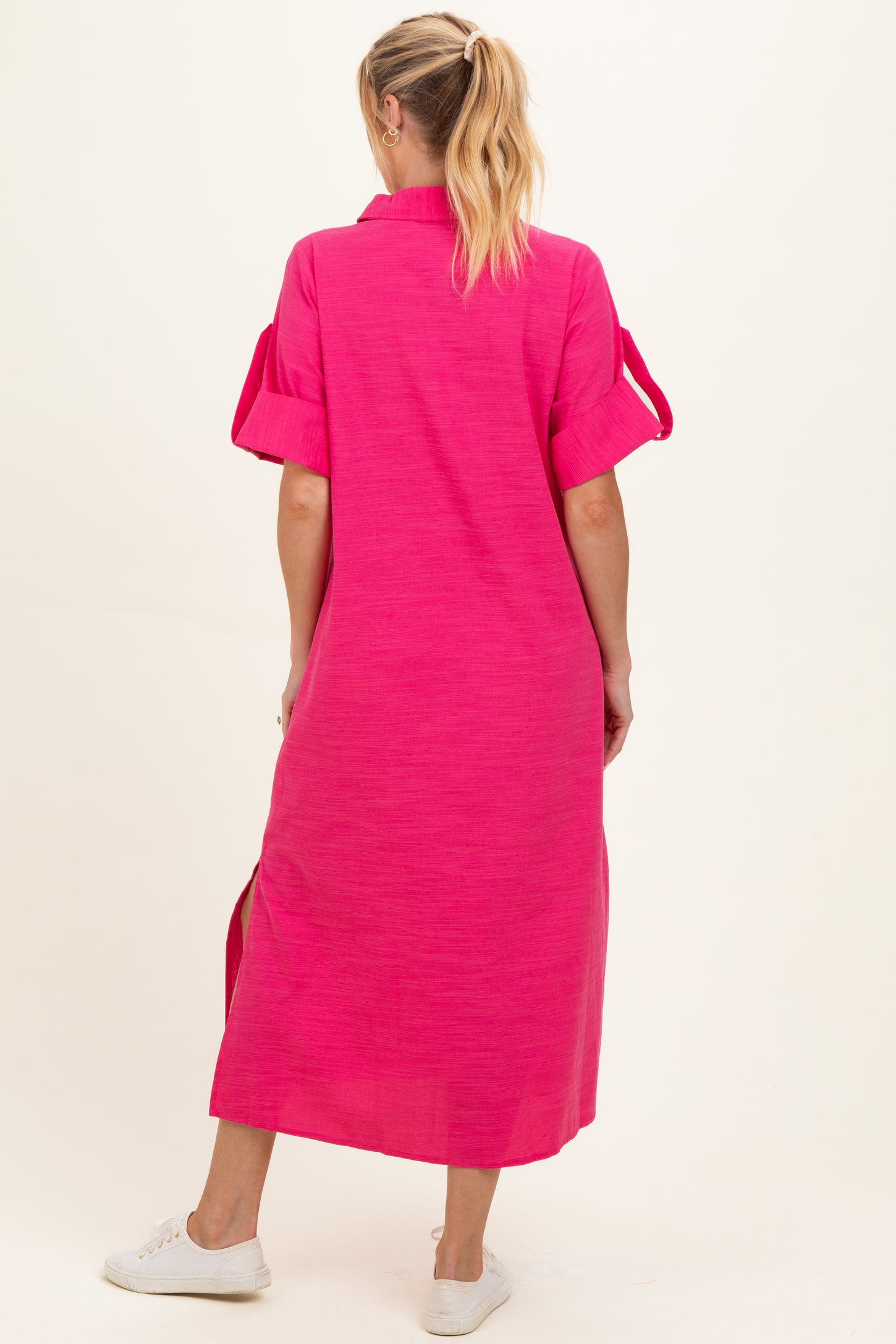 woman wearing a bright pink maternity maxi dress with short sleeves and a relaxed fit, showing off her baby bump