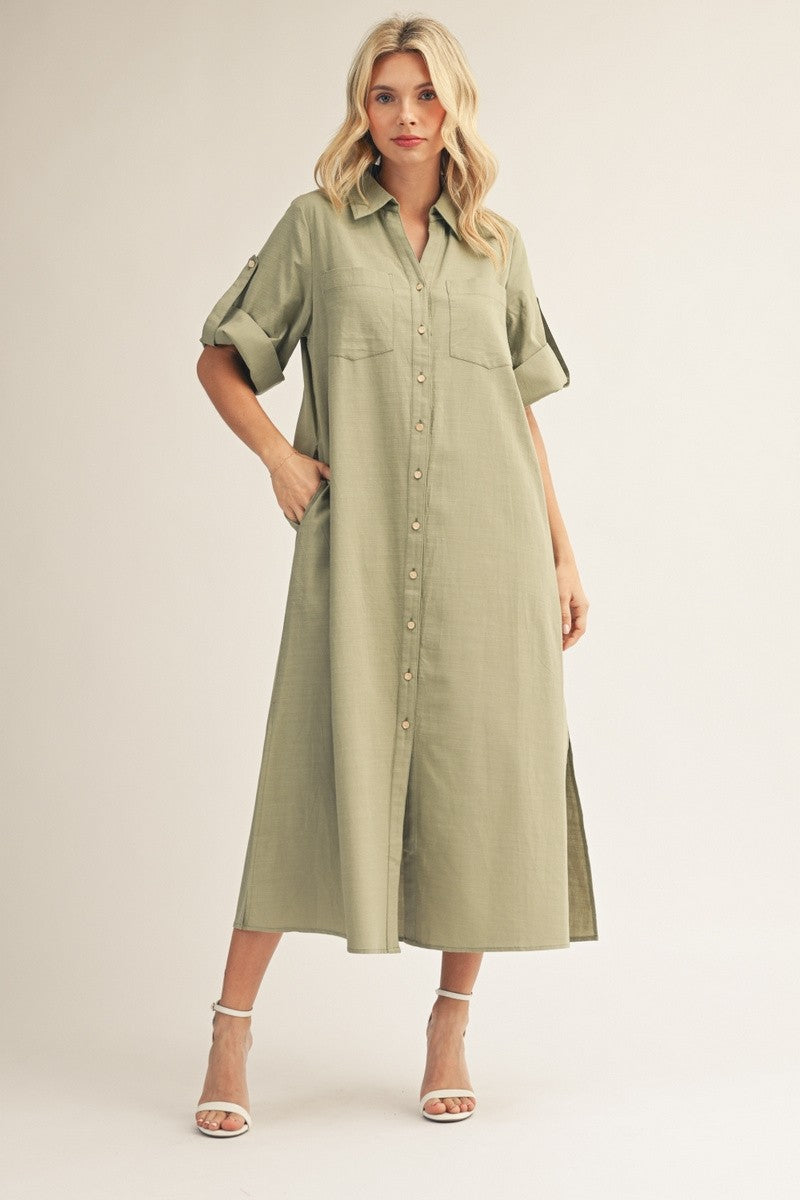 woman wearing a long green button-up shirt dress with short sleeves and side pockets