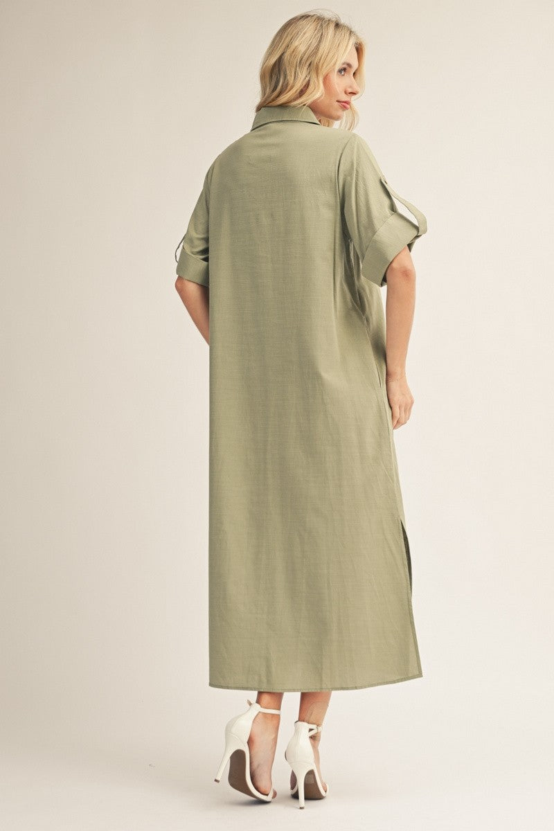 woman wearing an olive green maxi shirt dress with rolled sleeves and side slits, shown from the back with high heels